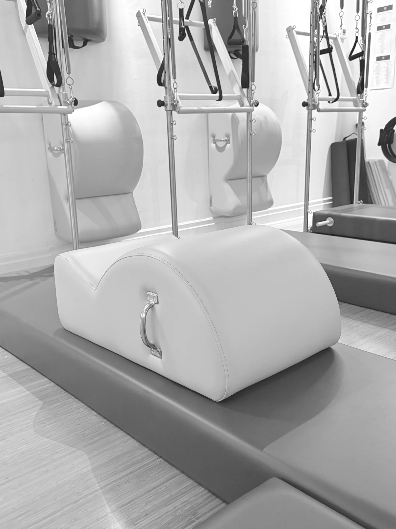 Pilates spine corrector on a padded mat, with wall-mounted Towers behind it