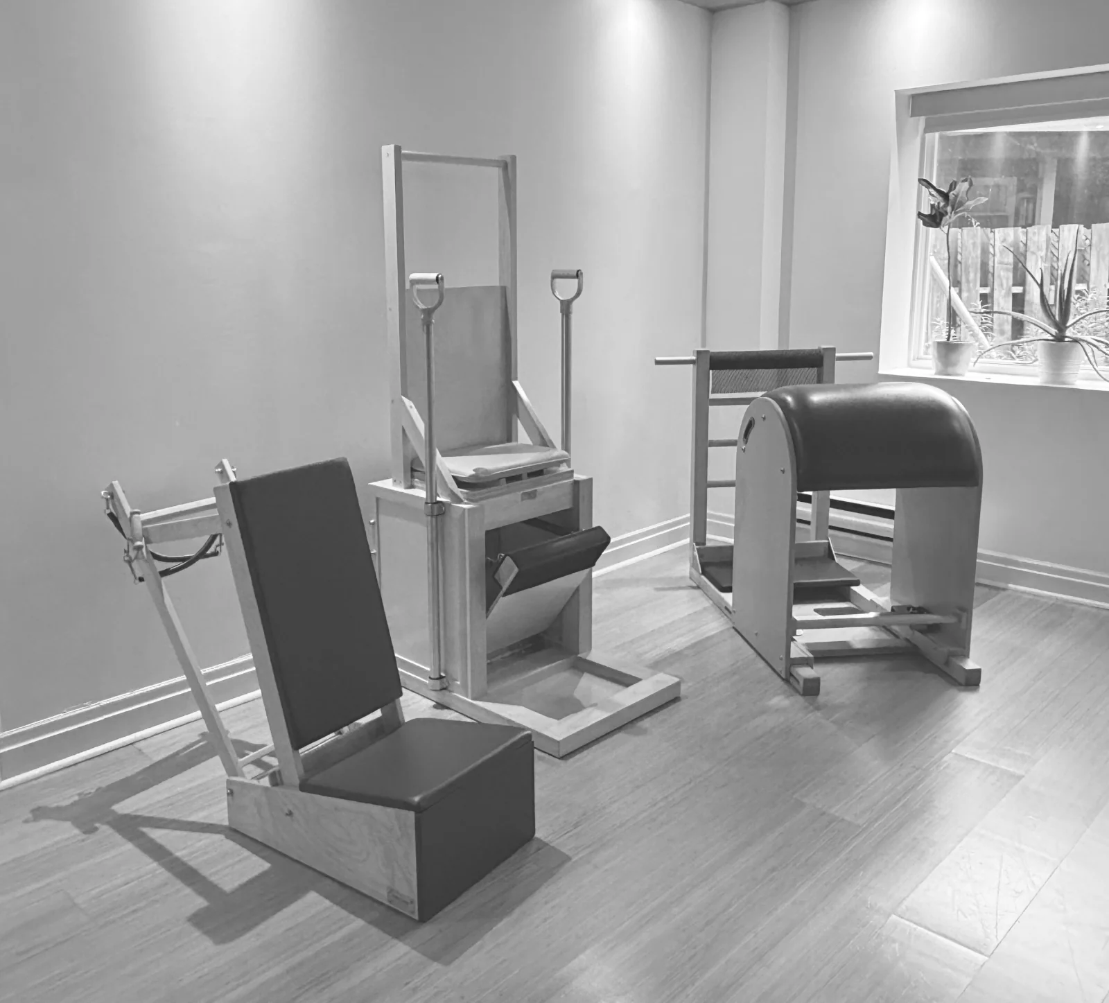 Pilates arm chair, high chair and Ladder Barrel beside a sunlit studio window