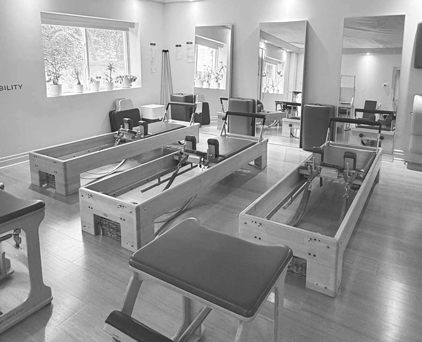 Three wooden Reformers with Pilates chairs and mirrors in the bright Kerr Village studio