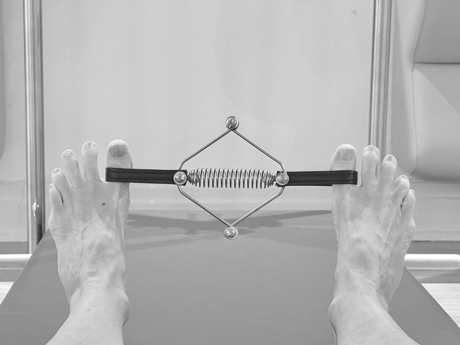 Close-up of feet using a small Pilates toe exerciser with a central spring
