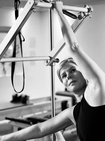 Client stretching sideways with one hand holding the Pilates push-through bar