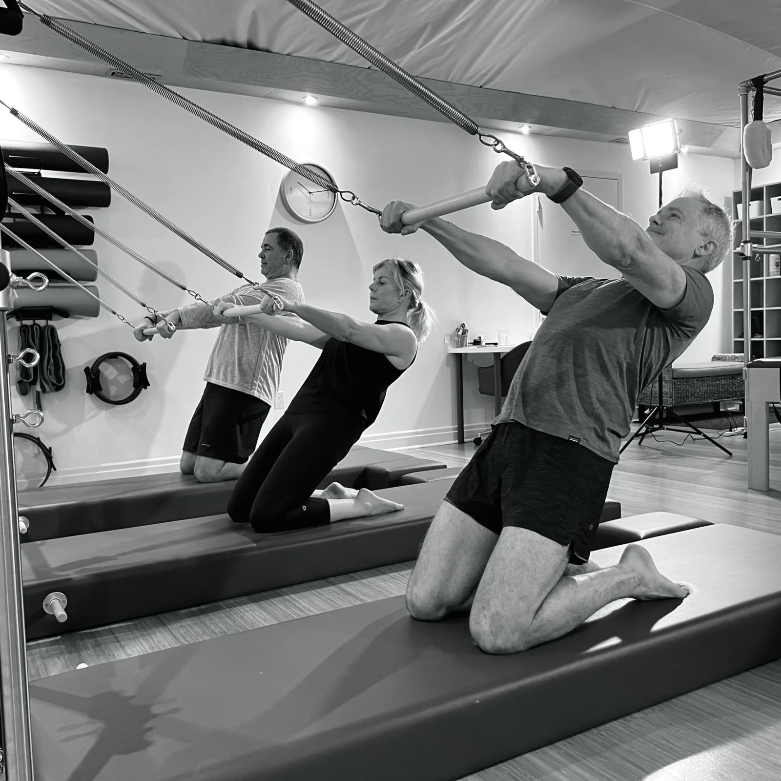 Three clients practising together with spring bars on Pilates Towers