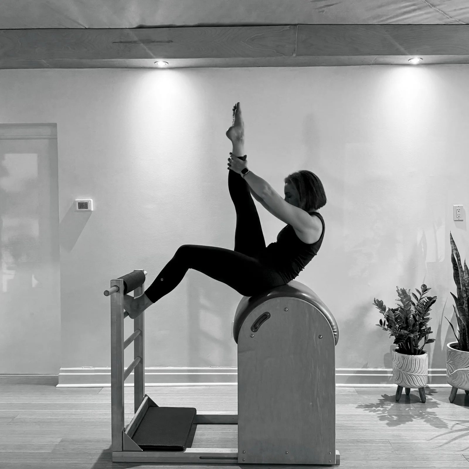 A woman practising Tree on the Ladder Barrel with one leg extended upward