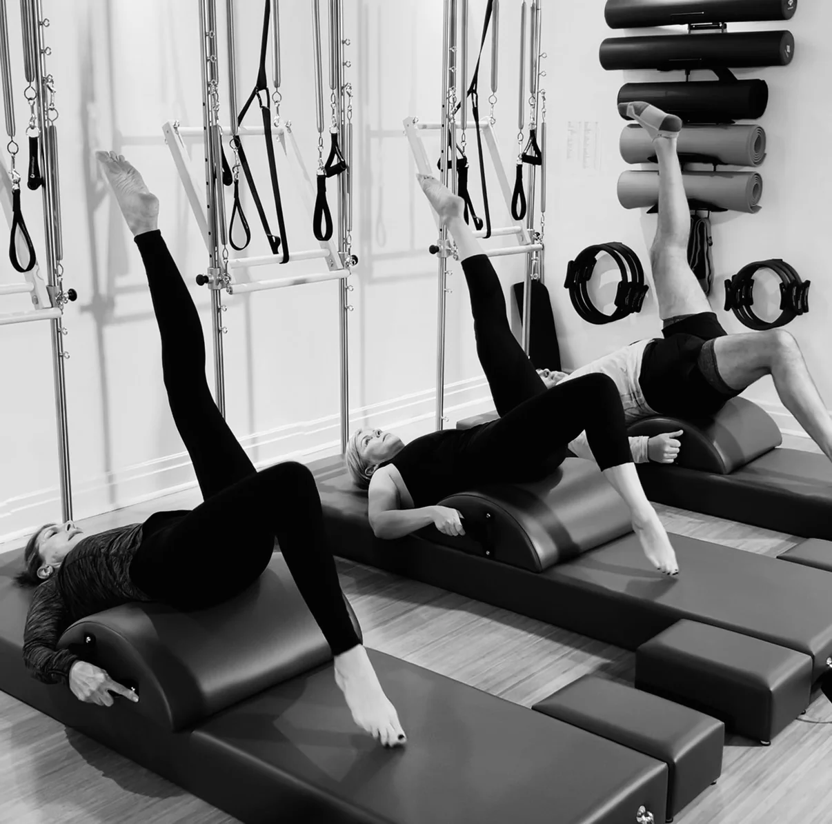Three clients practising leg movements while supported by spine correctors